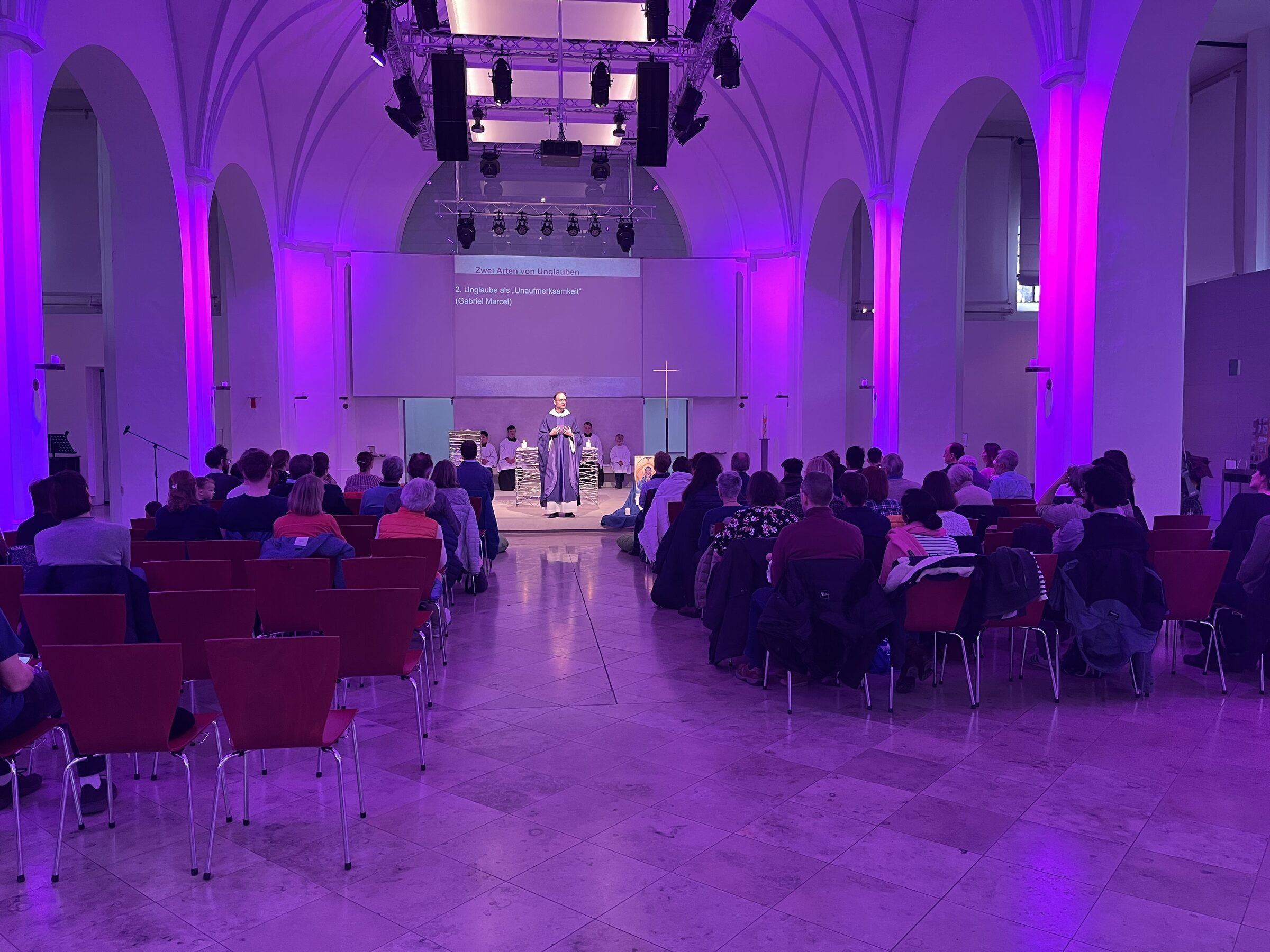 Gottesdienst in der Jugendkirche, der Saal in violettes Licht getaucht