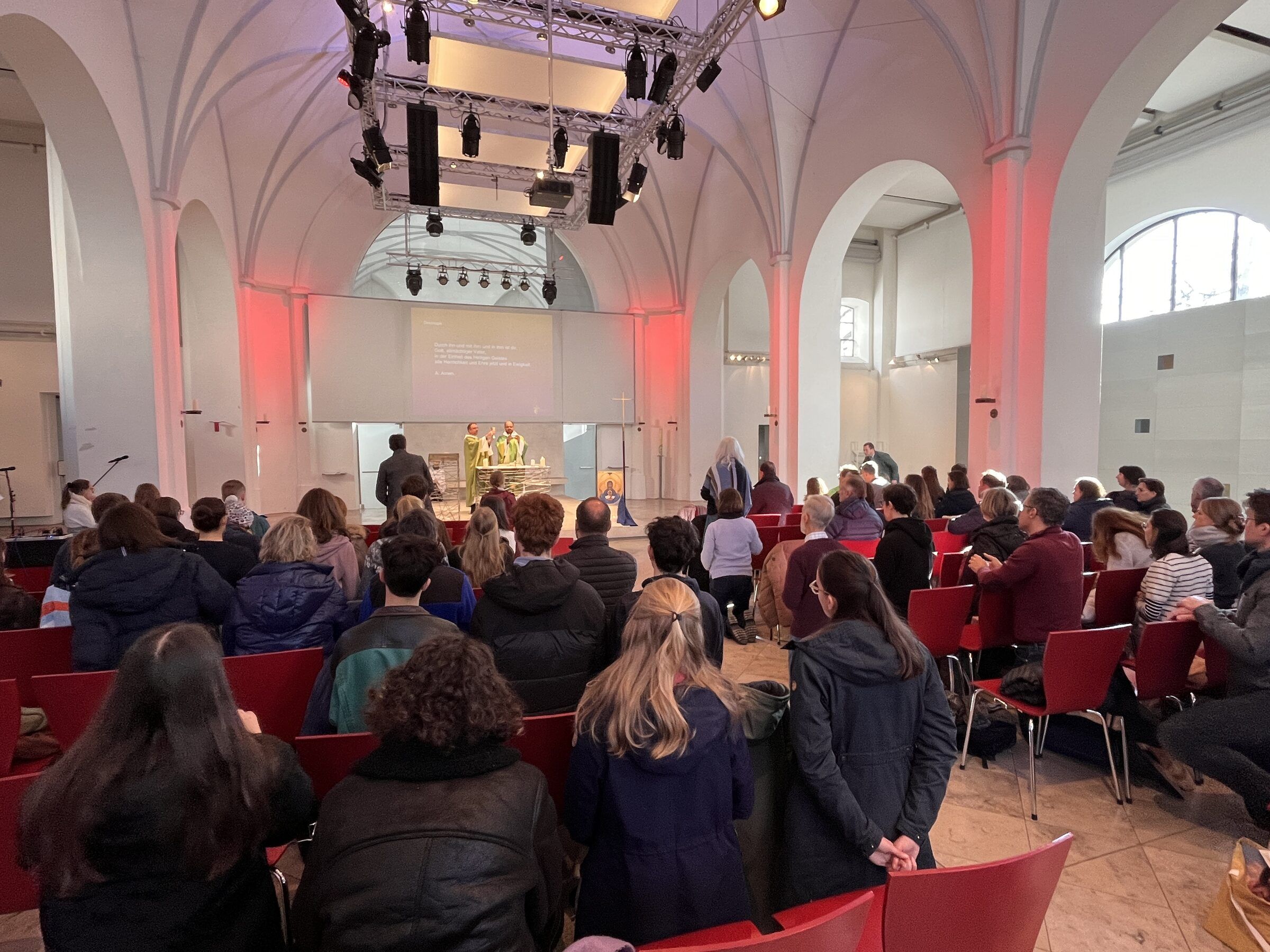 Volle Jugendkirche im rot-violetten Licht während des Gottesdienstes